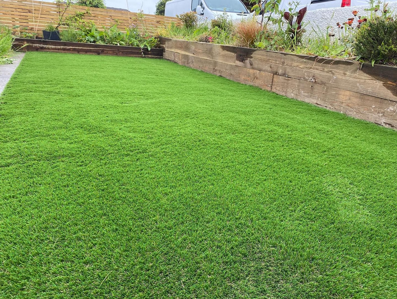 Green artificial lawn with timber sleeper borders